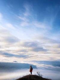 Woman standing on peak against sky