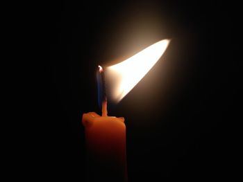 Close-up of illuminated candle in darkroom