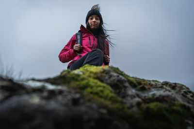 Portrait of woman standing on rock against sky