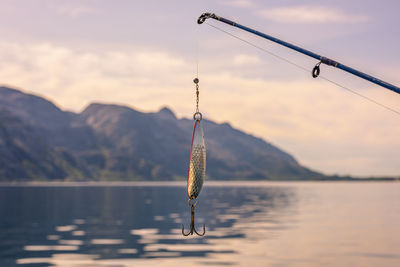 Fishing rod over lake against sky