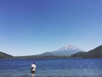 Rear view of man standing in front of lake