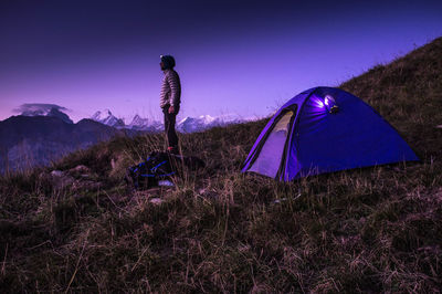 Man standing on grass by tent against sky