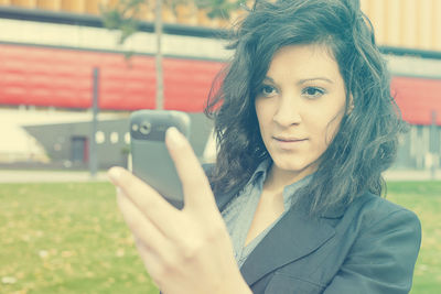 Close-up portrait of young woman using phone in city