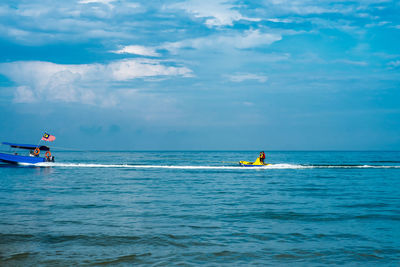 Rear view of people on boat in sea against sky