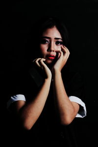 Portrait of sad woman against black background