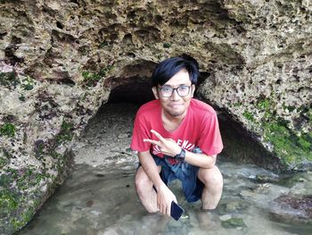 Portrait of young man sitting on rock