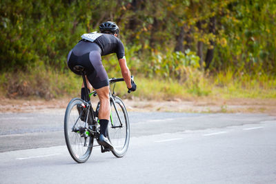 Rear view of man riding bicycle on road