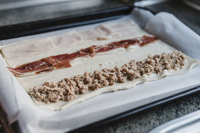 Dough with meat and ham on tray