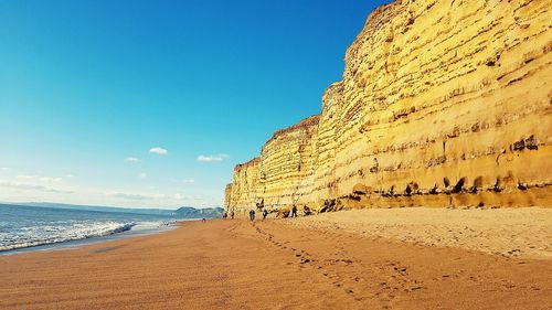 Scenic view of beach against blue sky on sunny day