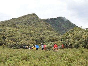 Group of people relaxing on mountain against sky