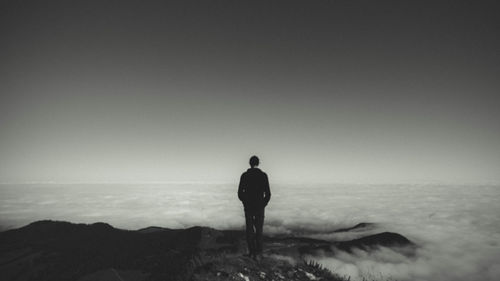 Rear view of silhouette man standing on sea against sky