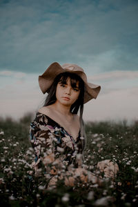 Portrait of young woman wearing hat standing on field