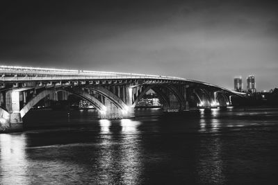 Bridge over river in city against sky at night