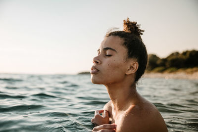Close-up of shirtless young woman swimming in sea