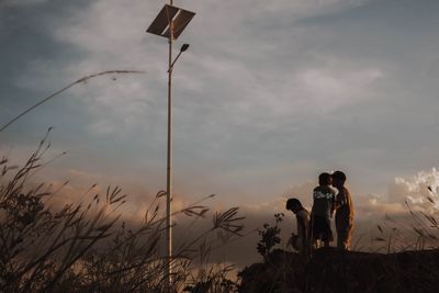 People standing on land against sky during sunset