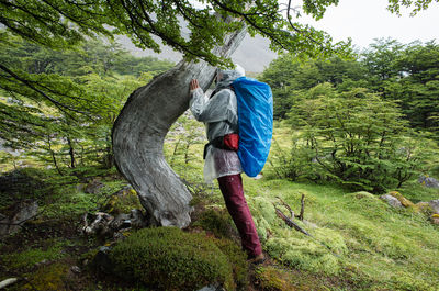 Side view full length of person standing by tree at forest