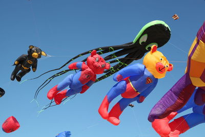 Assortment of colorful kites flying in clear blue sky