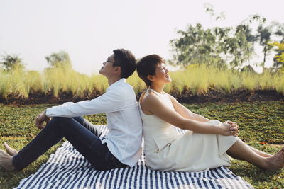 Rear view of couple sitting on field