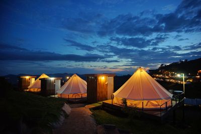 Illuminated tent on field against sky at night