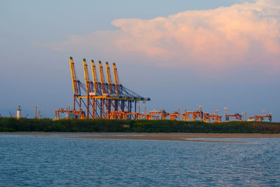 Traditional windmill on sea against sky during sunset