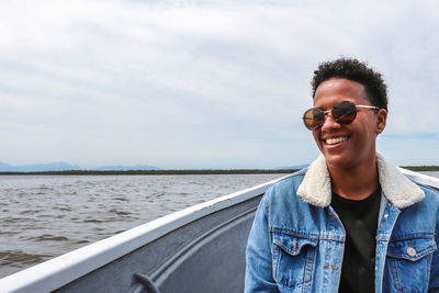 Portrait of young man wearing sunglasses against sea