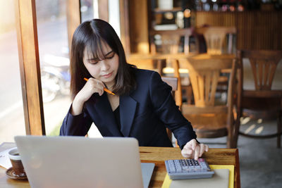 Young woman using phone while sitting on table