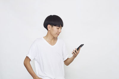 Mid adult man using smart phone against white background