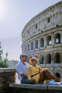 People sitting at historical building against sky