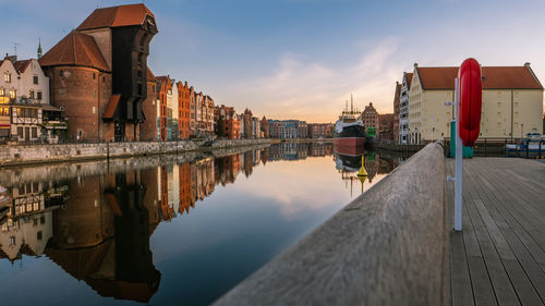 Reflection of buildings in lake against sky during sunset