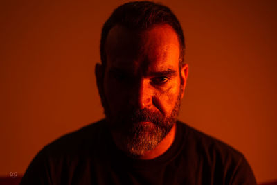 Close-up portrait of man against orange background