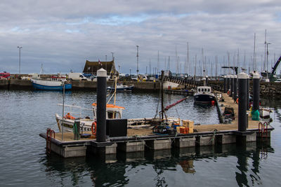 Boats moored at harbor against sky