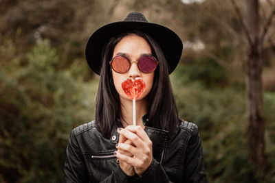 Portrait of woman wearing sunglasses holding heart shaped candy