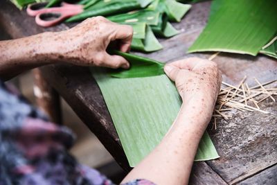 Cropped hand of woman holding banana leaf on table