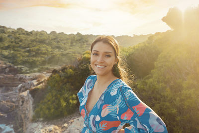 Portrait of young woman standing against mountain