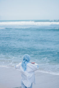 Rear view of woman standing at beach