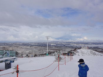 Rear view of people on snow covered mountain against sky