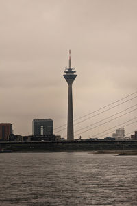 View of buildings by river against sky
