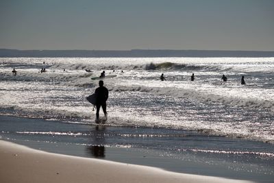 Silhouette surfers in sea