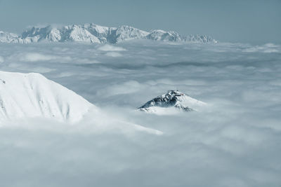 Snow covered mountain peaks reaching above a sea of clouds, gastein, austria