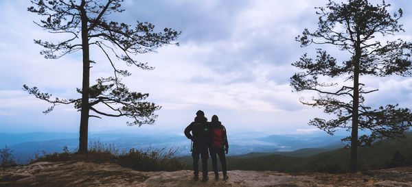 Rear view of man walking on mountain against sky