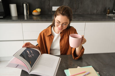 Young woman using mobile phone while sitting on table