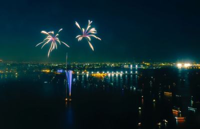 Firework display over river in city at night