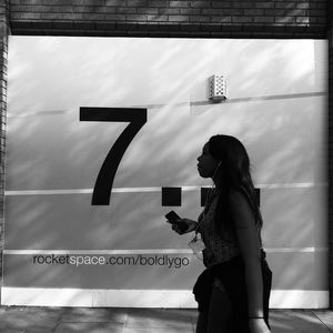 Side view of woman standing by text on wall