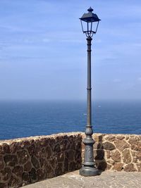 Street light by sea against sky