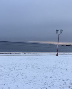 Street light by sea against sky during winter