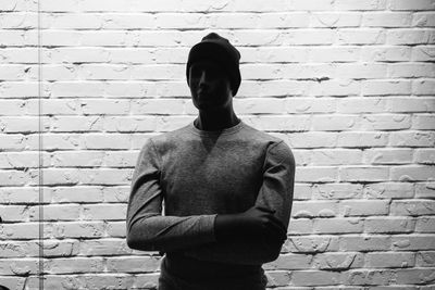 Young man standing against brick wall