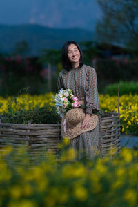 Woman standing by flower on field