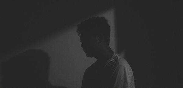 Silhouette man standing against wall in darkroom