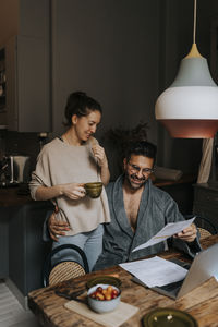 Smiling couple reading document while sitting at home