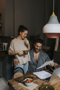 Smiling couple reading document while sitting at home